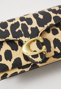 Leopardenmuster-Lederbörse in Beige und Schwarz, mit einem goldfarbenen Verschluss und einem markanten 'C'-Logo. Strukturiert Oberfläche und gestickte Kanten.