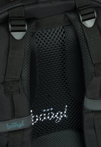 Interno di uno zaino nero con schienale in rete, spallacci regolabili e un logo con font corsivo. Materiale in tessuto testurizzato e resistente.