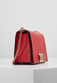 Rød lædertaske med en struktureret overflade, guld kædestropp og rektangulær form. Har en fremtrædende lukning i guld hardware.