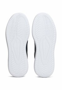 Suole di sneakers bianche con motivi di battistrada a onda e a chevron, con il marchio "Tommy Hilfiger" al centro.