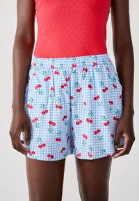 Lichtblauwe shorts met een kersenenprint tegen een achtergrond van ruitjes. Elastische tailleband voor comfort. Soepele, lichte stof.