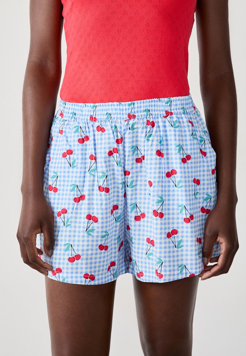 Lichtblauwe shorts met een kersenenprint tegen een achtergrond van ruitjes. Elastische tailleband voor comfort. Soepele, lichte stof.