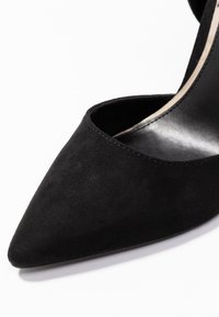 Černý nubukový vysoký podpatek s špičatou špičkou a hladkým vnitřním podšívkou. Obsahuje minimalistický design a jemné detaily šití.