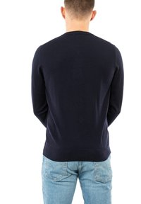 Maglione lavorato a maglia blu navy con collo rotondo e maniche lunghe, caratterizzato da una texture liscia e una silhouette aderente, indossato con jeans azzurri chiari.