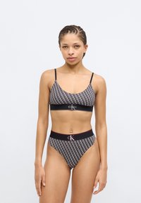 Σετ μαύρου και άσπρου μοτίβου με μπραλέτα και ψηλόμεσο εσώρουχο, με λωρίδα λογότυπου, λείο ύφασμα και λεπτές τιράντες.