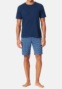Marineblå bomulds T-shirt med korte ærmer, parret med blå ternede shorts i forskellige nuancer af blå og en afslappet pasform.