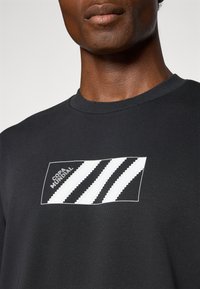 Sort bomulds t-shirt med en rektangulær hvid grafik, der har tre diagonale striber og "COPA MUNDIAL" tekst i en kontrasterende skrifttype.