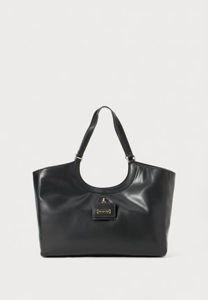 Fekete bőr tote táska fényes felülettel, ívelt tetejével, két vállpántjával és arany színű fémrészlettel az elején.