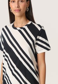 Sort og hvid stribet t-shirt med korte ærmer, der har diagonale linjer på et blødt stof. Rund halsudskæring og afslappet pasform.
