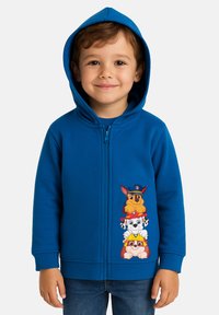 Felpa blu con zip che presenta una grafica di quattro cani stilizzati impilati verticalmente sul davanti. Tessuto morbido con una superficie liscia.