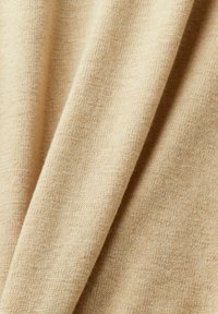 Tejido de punto beige con una textura fina; parece suave y liso; presenta sutiles variaciones de color en la superficie.