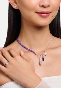 Schmuckset aus Sterlingsilber mit einer lila Perlenkette und Anhängern, darunter ein Stern, ein Kristallanhänger und eine dekorative Figur.