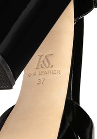 Black patent leather high-heeled shoe with a smooth, shiny finish. Inside, the sole displays "KS REAL LEATHER 37" embossed in gold.