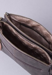 Dark leather bag with dual zip compartments, featuring a smooth texture and brown patterned lining. Metal hardware accents positioned at the top.