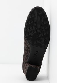 Semelle d'une chaussure à imprimé léopard marron, avec une semelle en caoutchouc noir, un talon carré, et les marquages "Gabor" et "air cube" visibles.