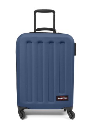 Blue hard-shell suitcase with vertical ridges, black accents, retractable handle, and four wheels for mobility. Brand logo on front.