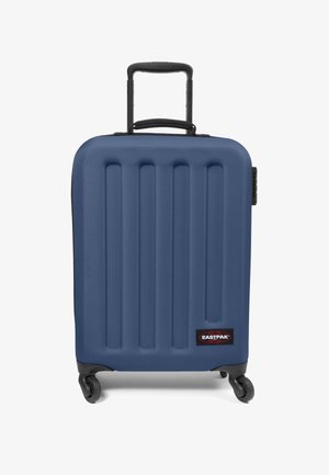 Blauer Hartschalentrolley mit vertikalen Rillen, schwarzen Akzenten, einem ausziehbaren Griff und vier Rädern für Mobilität. Markenlogo auf der Vorderseite.