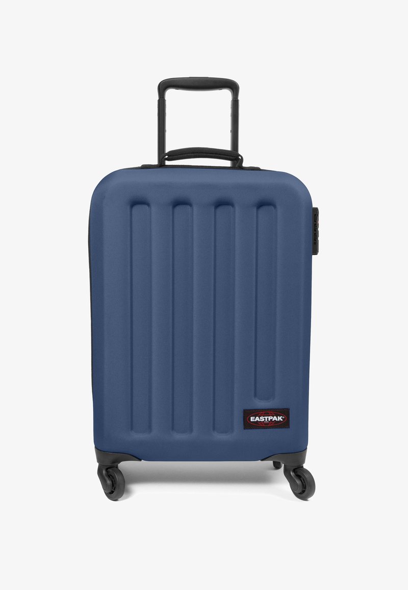 Maleta rígida azul con surcos verticales, acentos negros, asa retráctil y cuatro ruedas para movilidad. Logo de la marca en la parte frontal.