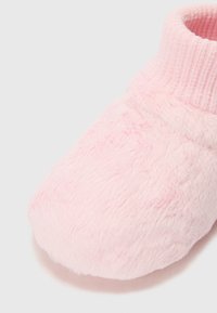 Rosa, pelsede tøffel med ribbestrikket ankelmansjett. Laget av myk stoff, med en rund tå og teksturert overflate for god komfort.