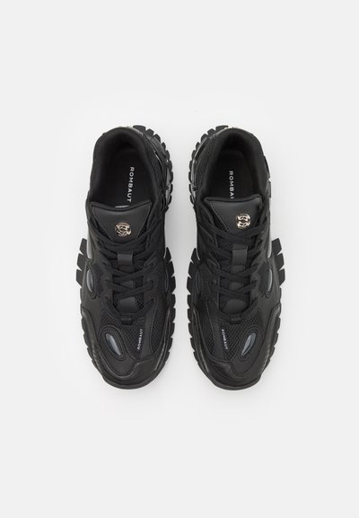 Black athletic shoes with a mesh upper, chunky rubber sole, and prominent tread. Features logo accents and reflective detailing on the sides.