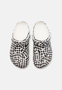 Black and white patterned clogs featuring a checkered design, smooth material, rounded toe, and textured inner sole with raised dots.