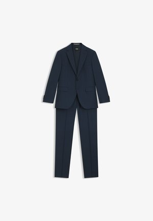 Abito blu navy caratterizzato da una giacca su misura con revers a punta, chiusura con un solo bottone e pantaloni frontali piatti. Il tessuto ha una trama sottile.