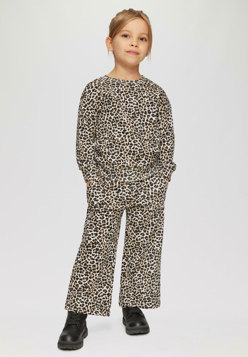 Luipaardprint lounge set in beige en bruin; heeft een ontspannen pasvorm, lange mouwen en elastische manchetten. Gepaarde met zwarte veterschoenen.