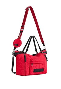 Czerwona pikowana torba na ramię z wieloma suwakami, czarnymi uchwytami, odpinanym czerwonym paskiem oraz małą, okrągłą saszetką przymocowaną do paska.