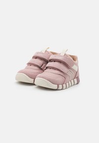 Zapatillas para niños pequeñas en color rosa con dos correas de gancho y bucle, punta redondeada y suela de goma que presenta un patrón texturizado en los laterales.