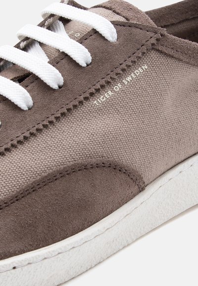 Αθλητικό παπούτσι από σουέτ και καμβά σε χρώμα ταουπέ, με λευκά κορδόνια και σόλα, με το λογότυπο "Tiger of Sweden" στο πλάι.