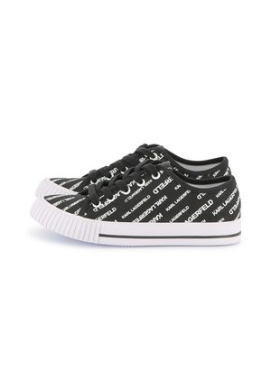 Baskets en toile noires avec un motif de texte blanc répété, orteils ronds et semelle en caoutchouc blanche avec des détails texturés.