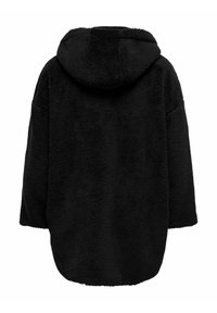 Melnā kapuce, pārmērīgi liela jaka, izgatavota no pūkaina, teksturēta auduma. Iespējo platu griezumu ar nolaistām plecu daļām un noapaļotu apakšmalu.