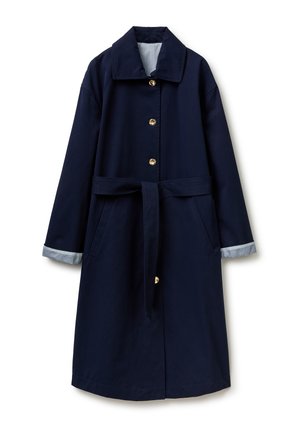 Long manteau bleu marine avec boutons dorés, ceinture assortie, poches latérales et doublures de poignets rayées bleu et blanc.