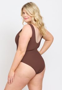 Brun ribbad enstycksswimewear med breda axelband och låg rygg. Slät textur med minimal hårdvara och en åtsittande design.