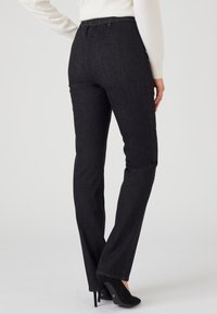 Pantalones de mezclilla negros con corte recto y cintura elástica. Tejido texturizado, costuras mínimas visibles y acabado suave.