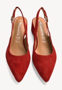Tacones slingback de ante rojo con puntera afilada, parte superior texturizada y un tacón pequeño. Cuenta con una correa ajustable en el tobillo con hebilla metálica.