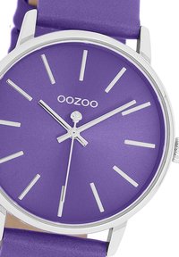 Purple quartz watch with a matching silicone strap, silver hour markers, and hands, featuring a simple round face and minimalist design.
