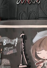 Zwarte leren tas met een gestructureerde textuur en geborduurde accenten, voorzien van de tekst "Beauty Begins Here" en een gestileerde silhouet van de Eiffeltoren.