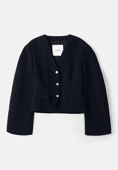 Juodas, trumpas švarkas su tekstūruotu audiniu, giliu V formos iškirpimu, penkiais sidabriniais mygtukais ir dviem kišenėmis su atlapais priekyje. Su pamušalu vidus.