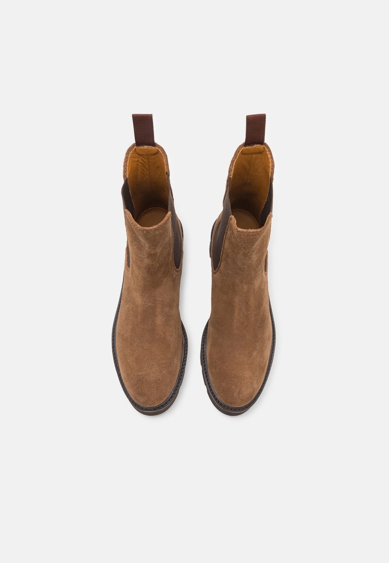 Ein Paar braune Wildleder Chelsea-Stiefel mit elastischen Seitenpaneelen und Zugschlaufen, von oben auf einem hellgrauen Hintergrund betrachtet.