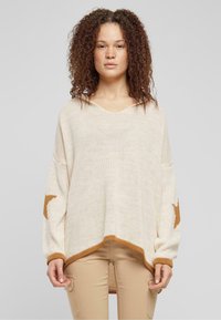 Beige knitted pullover featuring a V-neck, dropped shoulders, and brown star accents on sleeves. Hem has a contrasting brown trim.