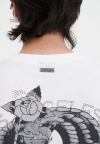 Witte katoenen T-shirt met een grijs grafisch ontwerp van een roos en een draak op de rug, met een zilveren label bij de hals.