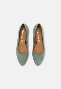 Ballerine in camoscio verde con punta affusolata, caratterizzate da una texture liscia e una soletta marrone. L'interno presenta il marchio e le informazioni sulla taglia.