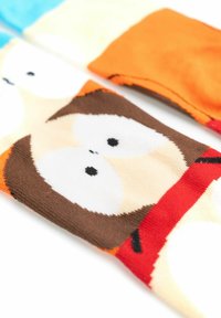 Calze colorate per bambini con un design di gufo cartone animato, con grandi occhi bianchi, un corpo marrone e dettagli arancioni. Texture morbida a maglia.