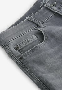 Jeans din denim gri cu o textură ușor uzată, având un buzunar frontal, închidere cu nasture și detalii de cusătură vizibile.