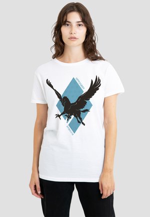 Woman wearing a white T-shirt with a black winged hippogriff silhouette over a blue diamond shape, text reads "HIPPOGRIFF" and "BUCEAR."