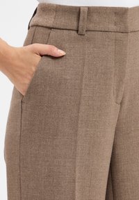 Bordeaux op maat gemaakte broek in gestructureerde stof met voorzakken, riemlussen en een vlakke voorzijde. Gladde afwerking en precieze stikseldetails.