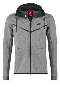 Grå zip-up hoodie gjord av mjukt material, med en svart huva, med dragkedjefickor och en Nike-logotyp på vänster bröst.