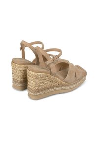 Sandales compensées en suède beige avec un design à brides croisées, un talon en jute tissé et une sangle de cheville réglable. Texture lisse et bout arrondi.