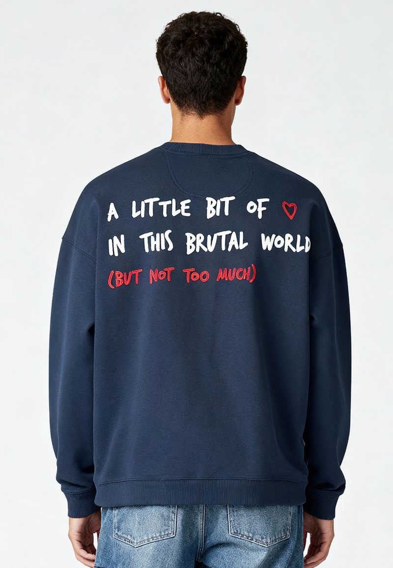 Tumši zila sporta krekls ar apaļu kakla izgriezumu, aizmugurē ir balti un sarkani uzraksti. Mīksta, teksturēta auduma, ar ribotām aprocēm un apakšmalu.